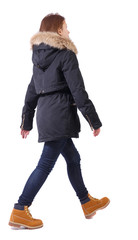 Naklejka premium Back view of going woman in jeans and winter jacket.