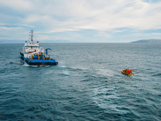 Industrial ship vessel and orange boat in sea. Industrial offshore working and searching for oil in...