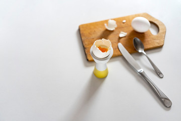 Soft boiled white eggs in egg cups on white table on wooden board. opy space, top view.