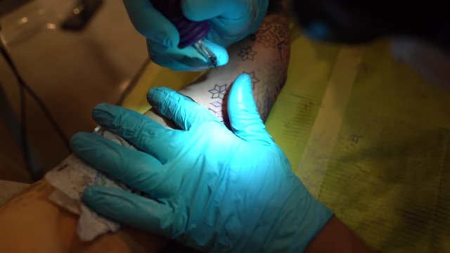Tattoo master makes a new tattoo on the hand of a girl