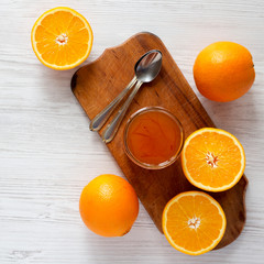 Top view, homemade orange marmelade in glass jar on a white wooden background. Flat lay, overhead, from above.