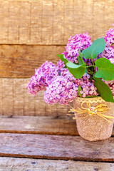 Ecology nature springtime concept. Bouquet of flowers beautiful smell violet purple lilac in vase on rustic wooden background. Inspirational natural floral spring blooming garden or park