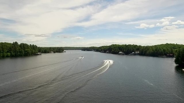 Aerial footage of two boats travelling down a calm lake.