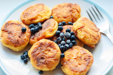 Delicious cottage cheese pancakes or curd fritters decorated honey and blueberry.