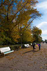 Beautiful sunny autumn day with the woman and the girl with the multi-colored balloons going along the embankment with trees in kontrovy lighting by the sun against the background of brightly blue sky