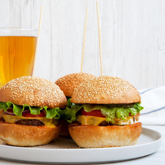 Cheeseburgers and glass of beer on a white wooden background, side view. Close-up.