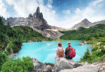 Fototapeta Travelers couple look at the mountain lake. Travel and active life concept with team. Adventure and travel in the mountains region in Dolomite alps, Italy obraz