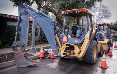 Backhoe parked and ready for use for road construction on suburban street
