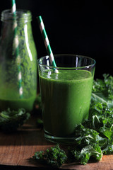 Green smoothie on rustic wooden table and black background