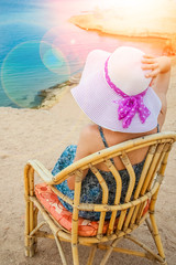 Stylish beautiful girl in hat on chair background