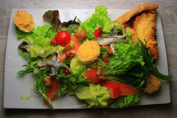 Salad prepared with mimosas eggs and a portion of onion pie in a French restaurant