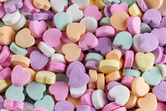 An assortment of conversation hearts taken from top down view.  Pastel colors.