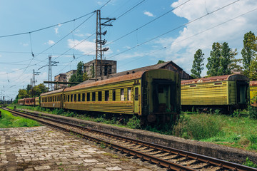 Naklejka premium Abandoned train on overgrown rail. Old rusty railway carriages in ghost town
