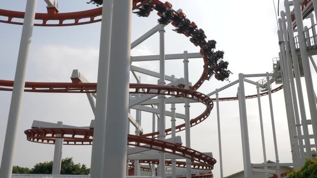 Slow motion shot of roller coaster train going down in a spiral while following the roller coaster circuit, Dream World, Thailand