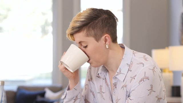 Pan up blonde woman on her phone and drinking coffee