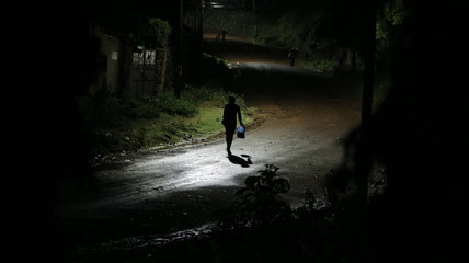 Back view of man going near male through the road at night in rain.