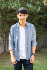 Beautiful portrait young handsome asian man standing and smile with sunlight at morning, male looking camera with happy, guy wear casual with cheerful, lifestyle and relax concept.
