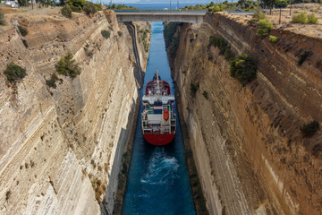 Large ship passing through Corinth canal. The Corinth Canal connects the Gulf of Corinth with the Saronic Gulf in the Aegean Sea. It separates Peloponnese from the Greek mainland.