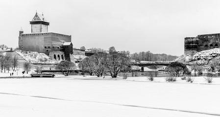 Narva River Promenade, Narva castle and river on a snowy winter day. Black and white.