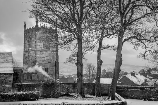 church tower or spire with roof tops of houses. snow with a winter sun. black and white.