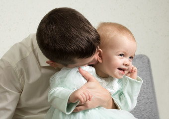 father plays with her little daughter, tickles her neck with kisses