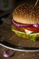 Hamburger with double cheese, red onions and tomatoes on a plate with white stars  on a table in the restaurant.