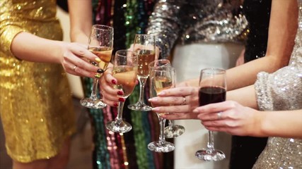 Slow motion of glasses with champagne. Unidentified women in cocktail dresses are celebrating with champagne. Office party