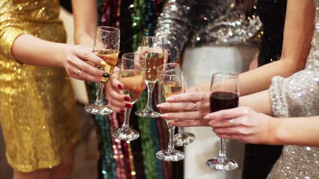 Slow motion of glasses with champagne. Unidentified women in cocktail dresses are celebrating with champagne. Office party
