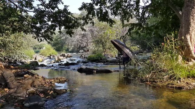 A man crossing a river stream of the Cauvery river carrying a coracle and a paddle in Hogenakkal, Tamilnadu, India