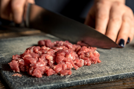 chef hands cut red meat on a board