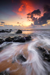 A scenery of sunrise with amazing unique rock formation and beautiful  flow of wave at Kemasik beach, Terangganu Malaysia. Soft focus during long exposure shot.