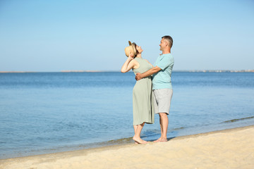 Happy mature couple at beach on sunny day