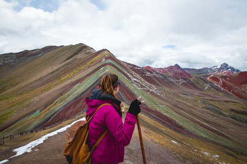 Woman contemplating the view of Vinicunca (rainbow mountain) after a long hike.