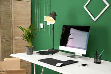 Stylish workplace with modern computer near color wall. Space for text