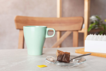 Saucer, spoon with used teabag and cup on table. Space for text