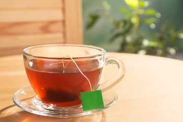 Brewing tea with bag in cup on table. Space for text