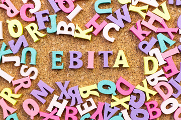 Color alphabet in word EBITA (abbreviation of  earnings before interest, taxes and amortization) with another letter as frame on cork board background