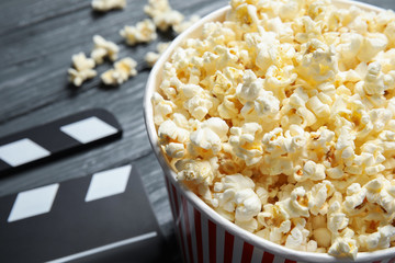 Fresh tasty popcorn in bucket on wooden background, closeup with space for text. Cinema snack