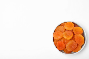 Bowl of dried apricots on white background, top view with space for text. Healthy fruit