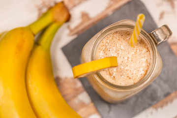 From above tasty fresh drink in glass mug with plastic tube and slice of fruit on coaster on wood table 