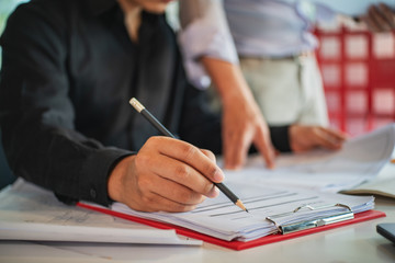 Businessman writing note with pencil on paper.