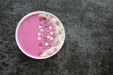 Happy Valentine's breakfast bowl. Pink smoothie bowl with decorations hearts.