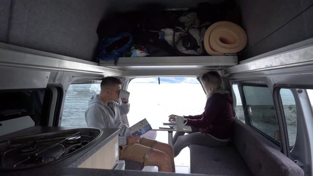 Young attractive couple sitting in back of motorhome by Lake Wakatipu, Queenstown, New Zealand