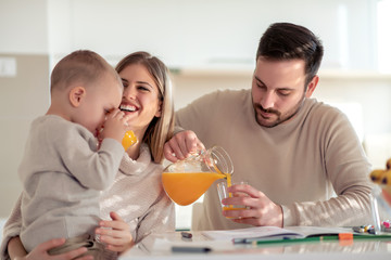 Obraz na płótnie Canvas Family with child having fresh fruit juice at home