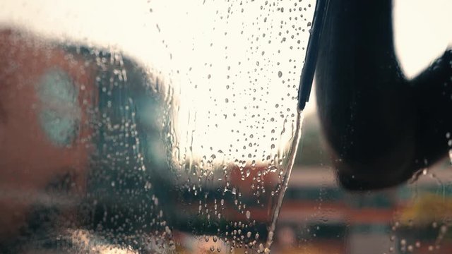 View of worker cleaning office windows outside, squeegee water from glass.