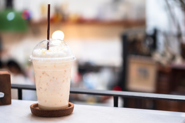 Iced milk tea with honey in plastic glass on blurred background of restaurants, Beverage summer cool drinks, Free copy space, Clipping path.