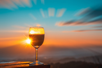 Red wine glass with the sunrise overlooking the mountains in northern of Thailand.