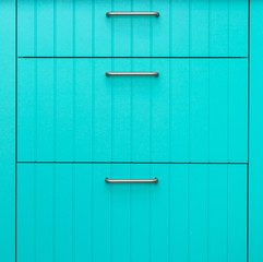 Blue wooden facade of kitchen cabinets made of thin strips with chrome handles.