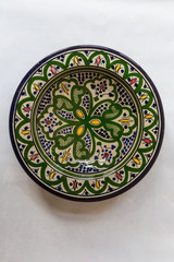 a white round plate with floral and line pattern on white background