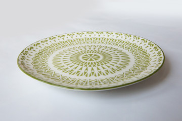 Fototapeta na wymiar a white round plate with floral and line pattern on white background